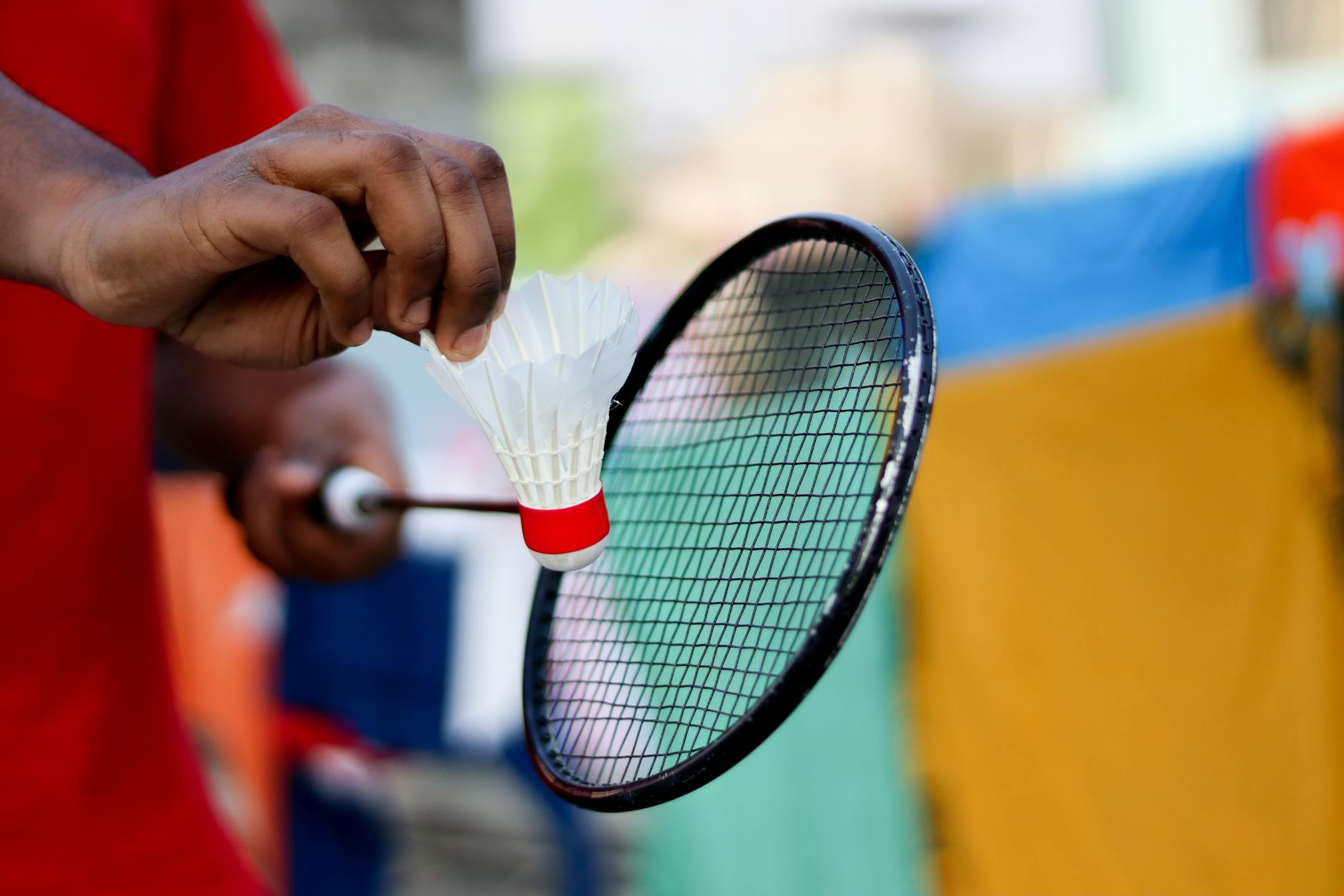 Pemula memegang raket badminton dengan grip forehand yang benar di lapangan indoor