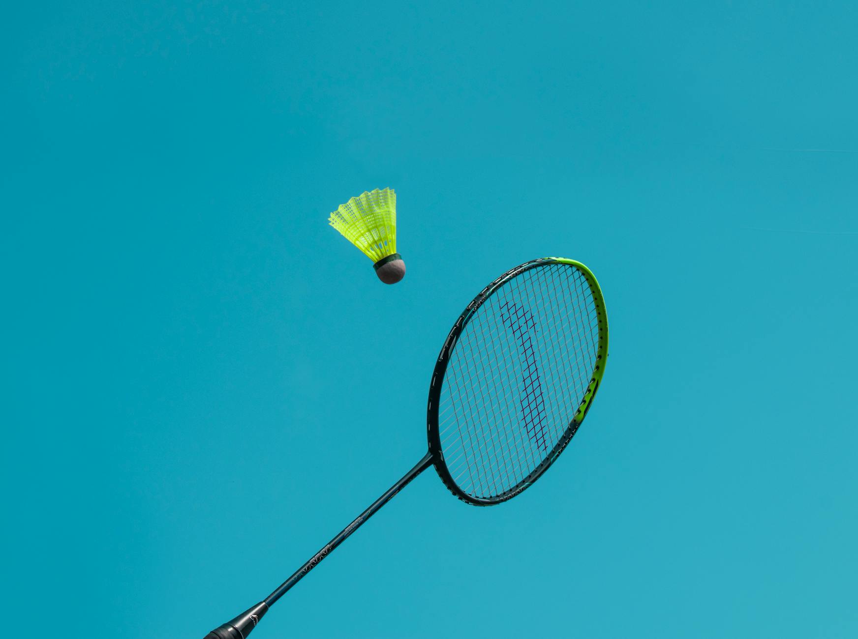 Pemain badminton melakukan clear shot tinggi ke belakang lapangan